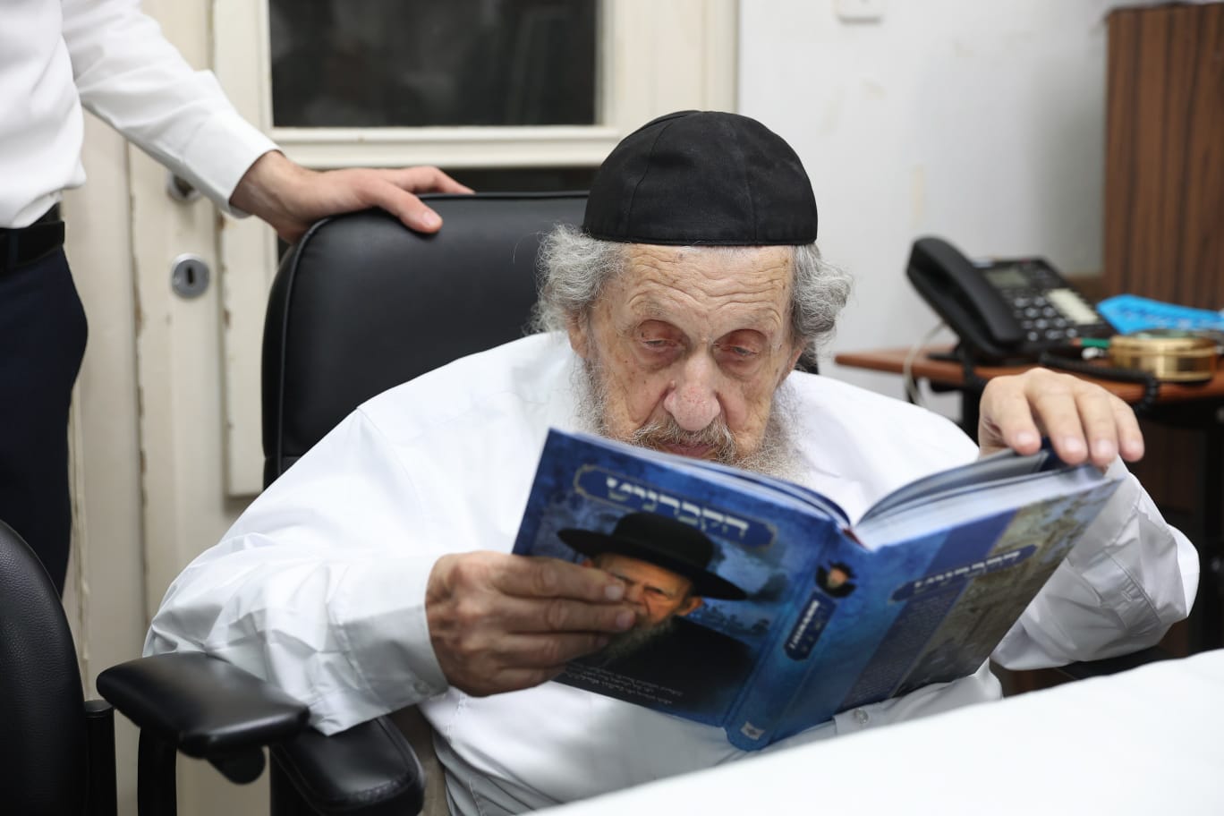 מרן הגרדל מעיין בספר החדש. המצלם